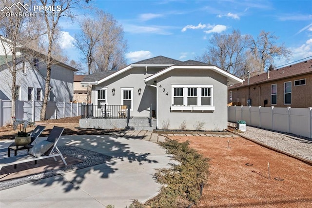 rear view of property with fence, a patio, and stucco siding