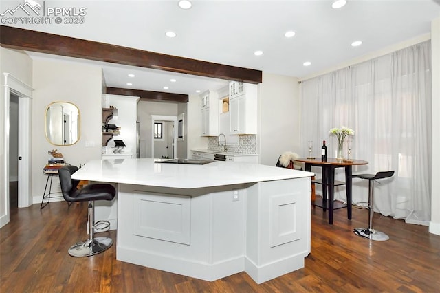 kitchen featuring light countertops, beamed ceiling, white cabinetry, and decorative backsplash