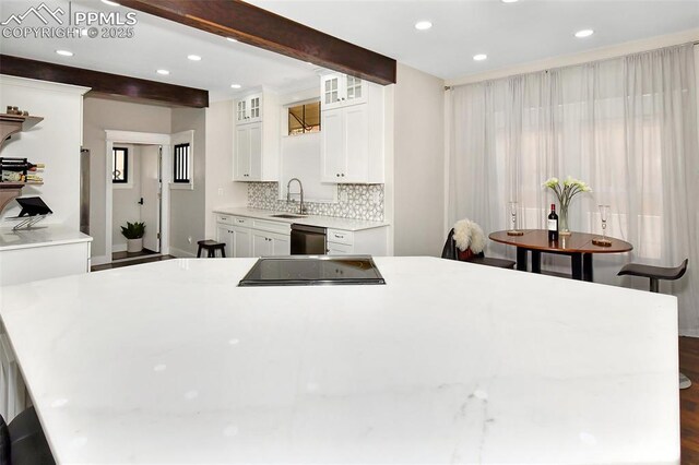 kitchen with tasteful backsplash, dishwasher, beam ceiling, white cabinetry, and a sink