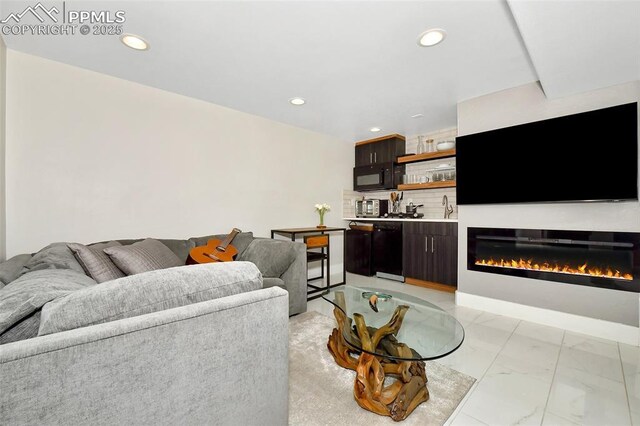 living room with marble finish floor, recessed lighting, and a glass covered fireplace