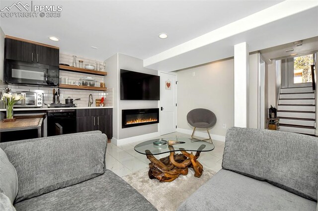 living room featuring marble finish floor, recessed lighting, a glass covered fireplace, baseboards, and stairs