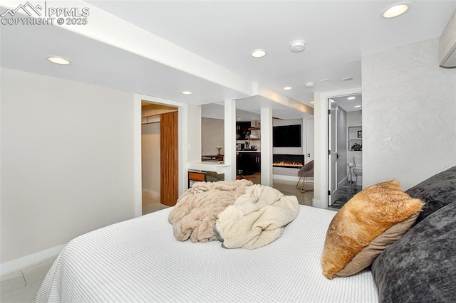 bedroom with a lit fireplace and recessed lighting