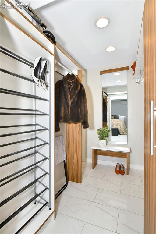 mudroom with recessed lighting, marble finish floor, and baseboards