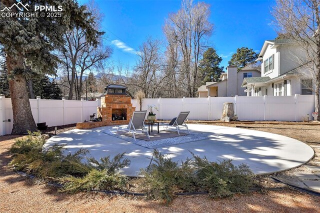 view of patio / terrace with a fenced backyard and an outdoor fireplace