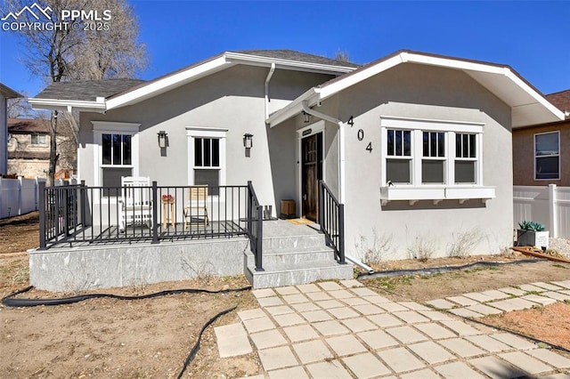 view of front of home with roof with shingles, fence, and stucco siding