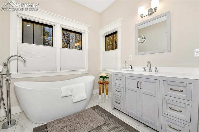 bathroom with a freestanding bath, marble finish floor, vanity, and baseboards