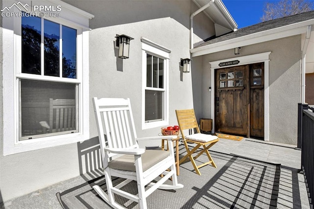 property entrance with covered porch, a shingled roof, and stucco siding