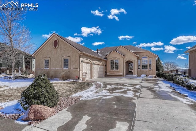 view of front of home with concrete driveway, an attached garage, and stucco siding