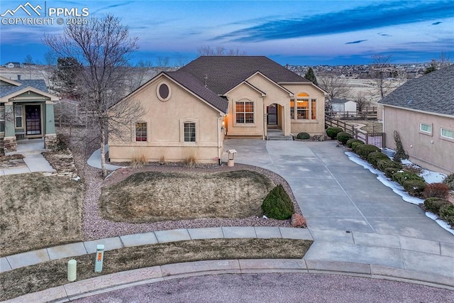 french provincial home featuring driveway, fence, and stucco siding