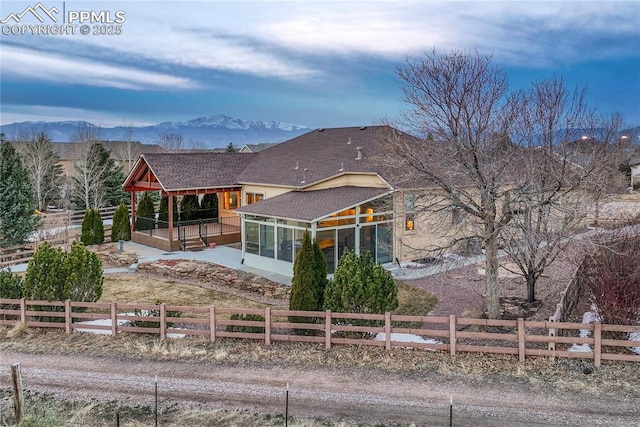 rear view of property with a mountain view, fence private yard, and a sunroom