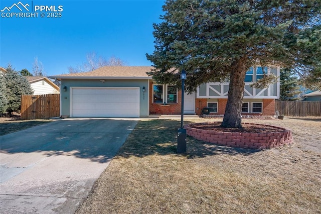 view of front of home featuring driveway, brick siding, an attached garage, and fence