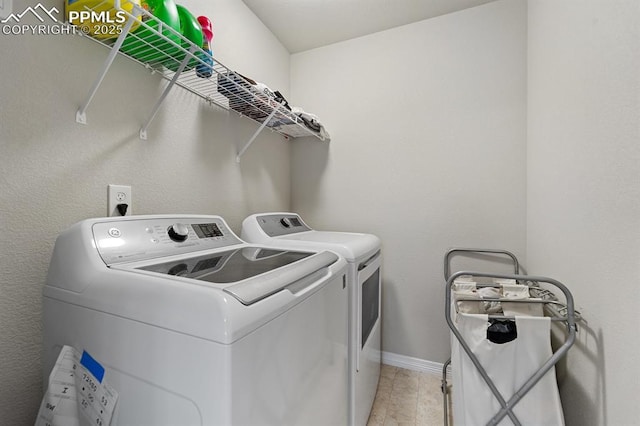 clothes washing area featuring baseboards, laundry area, light wood-type flooring, and washer and dryer