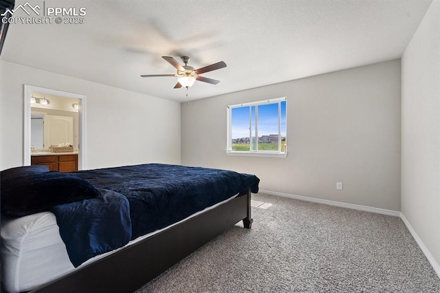 carpeted bedroom featuring ensuite bath, baseboards, and a ceiling fan