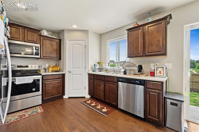 kitchen featuring recessed lighting, stainless steel appliances, a sink, light countertops, and dark wood finished floors