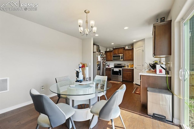 dining area with baseboards, dark wood-style flooring, visible vents, and an inviting chandelier