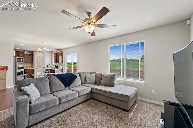 living area with baseboards and ceiling fan with notable chandelier