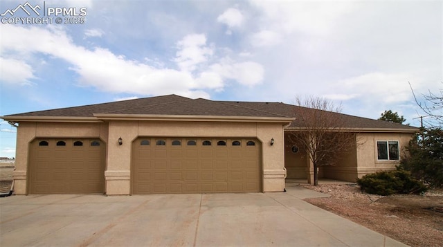 view of front facade featuring a garage, concrete driveway, roof with shingles, and stucco siding