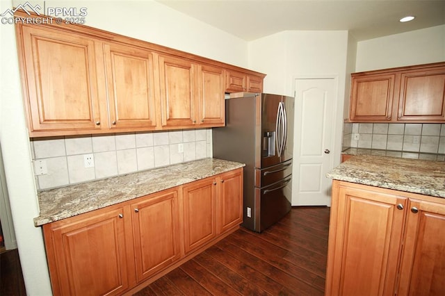 kitchen featuring dark wood-style flooring, brown cabinets, light stone countertops, and stainless steel fridge with ice dispenser