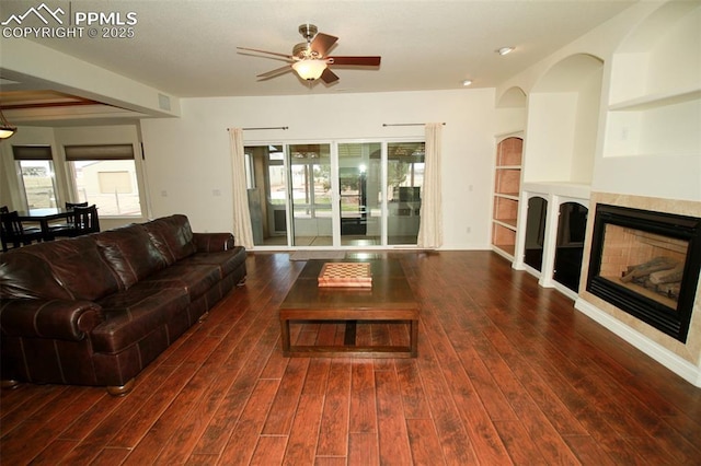 living area with plenty of natural light, a tiled fireplace, and wood finished floors