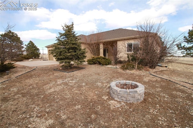 view of front of house with driveway, an outdoor fire pit, an attached garage, and stucco siding