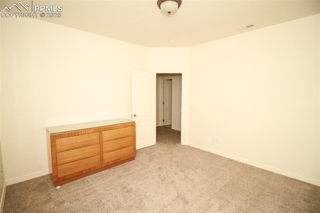 empty room featuring visible vents, baseboards, and light colored carpet