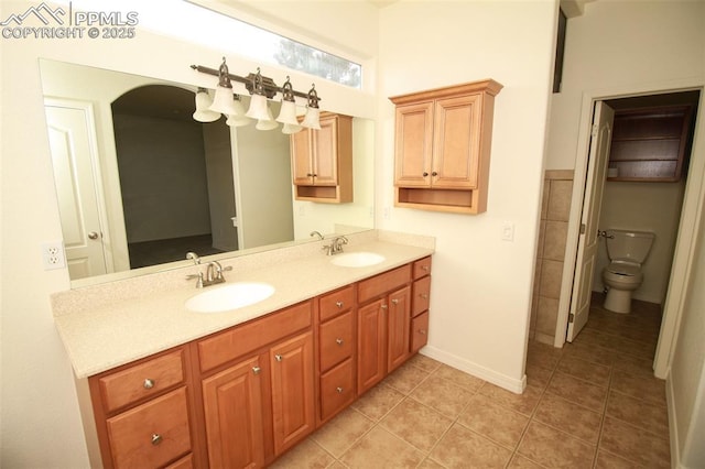 full bath with double vanity, tile patterned flooring, toilet, and a sink