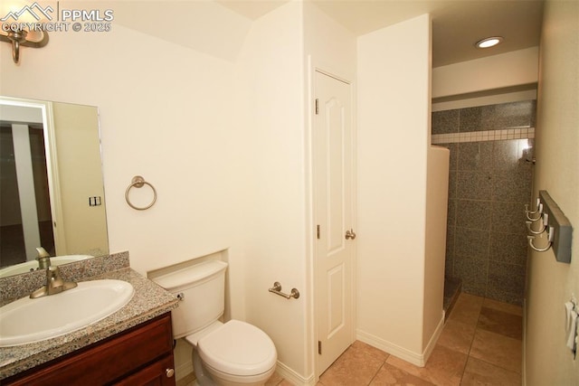 bathroom featuring baseboards, toilet, tile patterned floors, a tile shower, and vanity