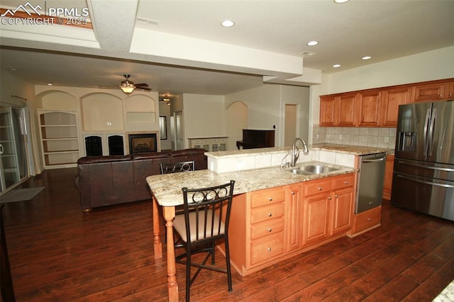 kitchen with stainless steel appliances, backsplash, dark wood-type flooring, open floor plan, and a sink