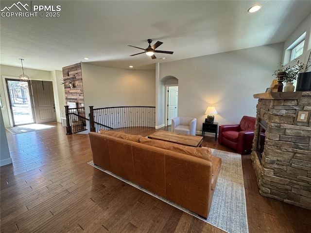 living area featuring arched walkways, a fireplace, dark wood finished floors, and a wealth of natural light