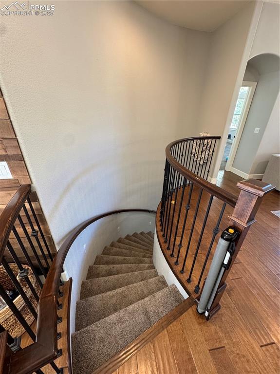 staircase featuring arched walkways and wood finished floors