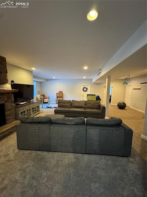 living room featuring recessed lighting, baseboards, dark colored carpet, and a stone fireplace