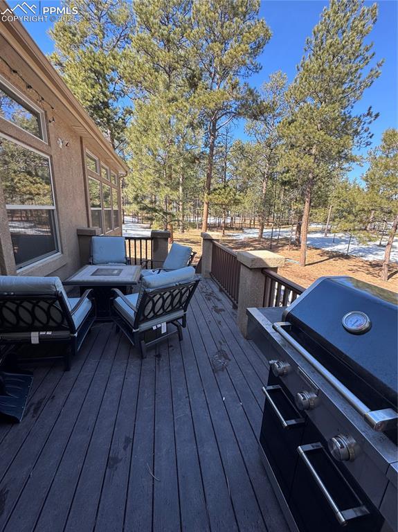 wooden deck with an outdoor hangout area and a grill