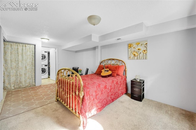 bedroom with carpet floors, visible vents, a textured ceiling, and stacked washing maching and dryer