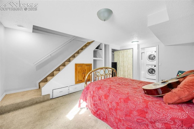 bedroom featuring carpet, baseboards, a textured ceiling, and stacked washer and clothes dryer