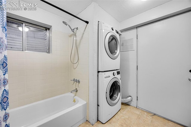 laundry room featuring laundry area, a textured ceiling, and stacked washer / drying machine