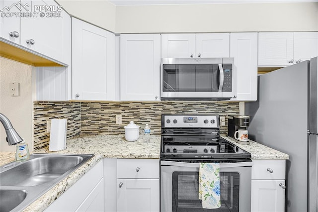 kitchen with light stone counters, stainless steel appliances, a sink, white cabinetry, and decorative backsplash