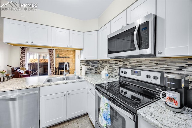 kitchen featuring appliances with stainless steel finishes, white cabinets, a sink, and backsplash