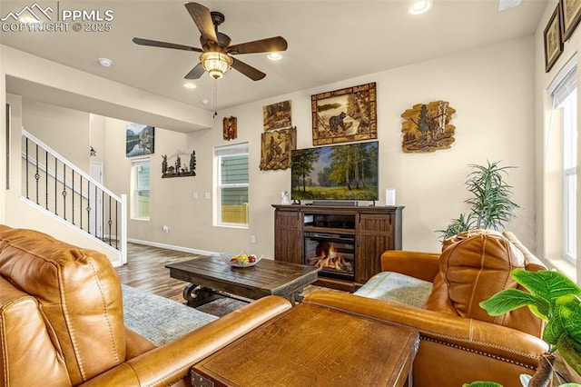 living area with a glass covered fireplace, stairway, recessed lighting, and wood finished floors