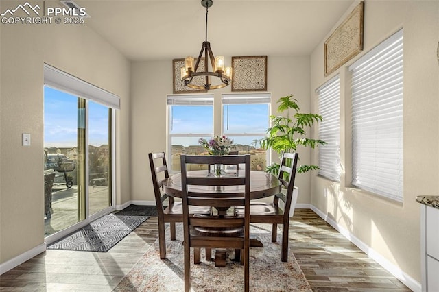 dining space with wood finished floors, baseboards, and an inviting chandelier