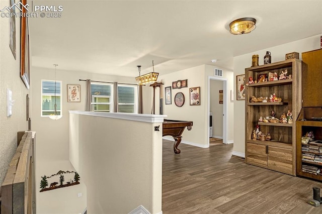 hall featuring baseboards, visible vents, dark wood-type flooring, and an upstairs landing