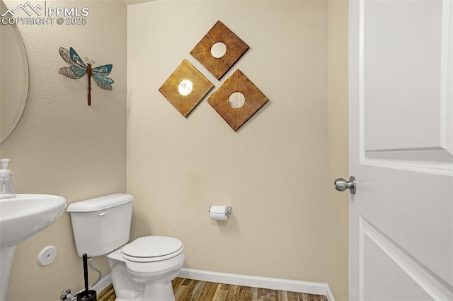 bathroom featuring toilet, baseboards, and wood finished floors