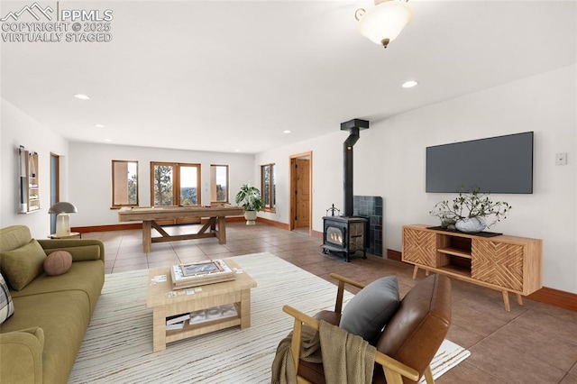 living area with recessed lighting, a wood stove, tile patterned flooring, and baseboards