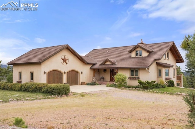 view of front of home with a chimney, stucco siding, a garage, driveway, and a tiled roof