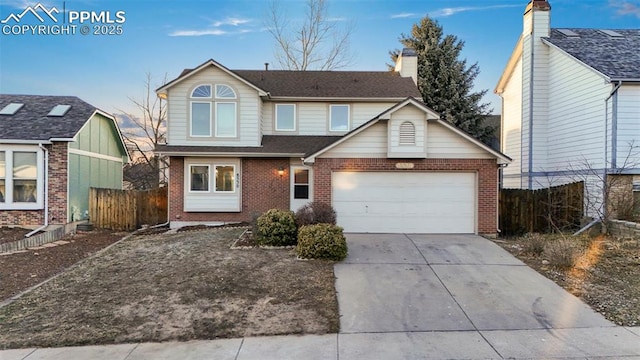 traditional home with brick siding, a chimney, concrete driveway, an attached garage, and fence