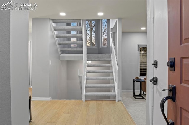 stairway with baseboards, wood finished floors, and recessed lighting