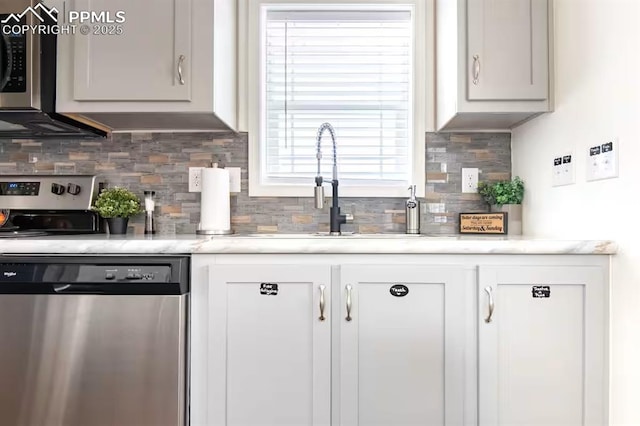 kitchen featuring white cabinetry, appliances with stainless steel finishes, decorative backsplash, and a sink