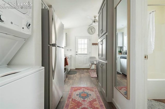 clothes washing area with laundry area, wood finished floors, a sink, and stacked washer and clothes dryer