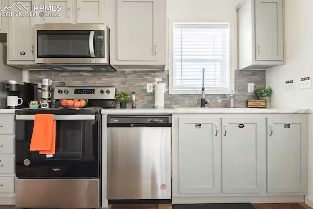 kitchen with a sink, stainless steel appliances, light countertops, white cabinetry, and backsplash