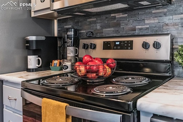 kitchen featuring tasteful backsplash, black microwave, white cabinets, and stainless steel electric stove