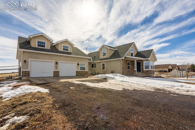 view of front facade with stone siding, an attached garage, driveway, and stucco siding